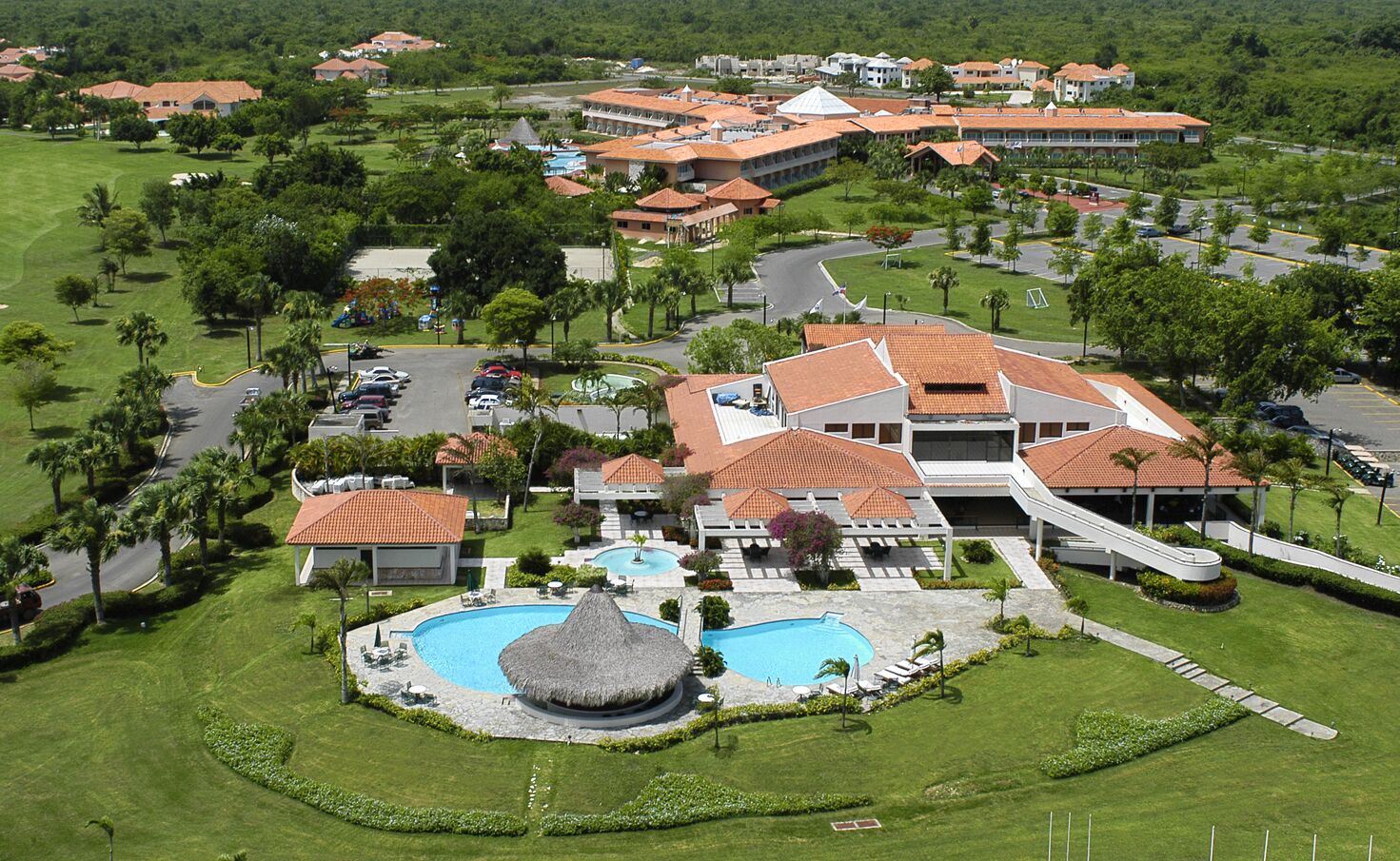 Un resort con piscina centrale, diversi edifici e un campo da golf.