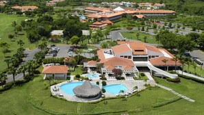 Een resort met een centraal zwembad, meerdere gebouwen en een golfbaan.
