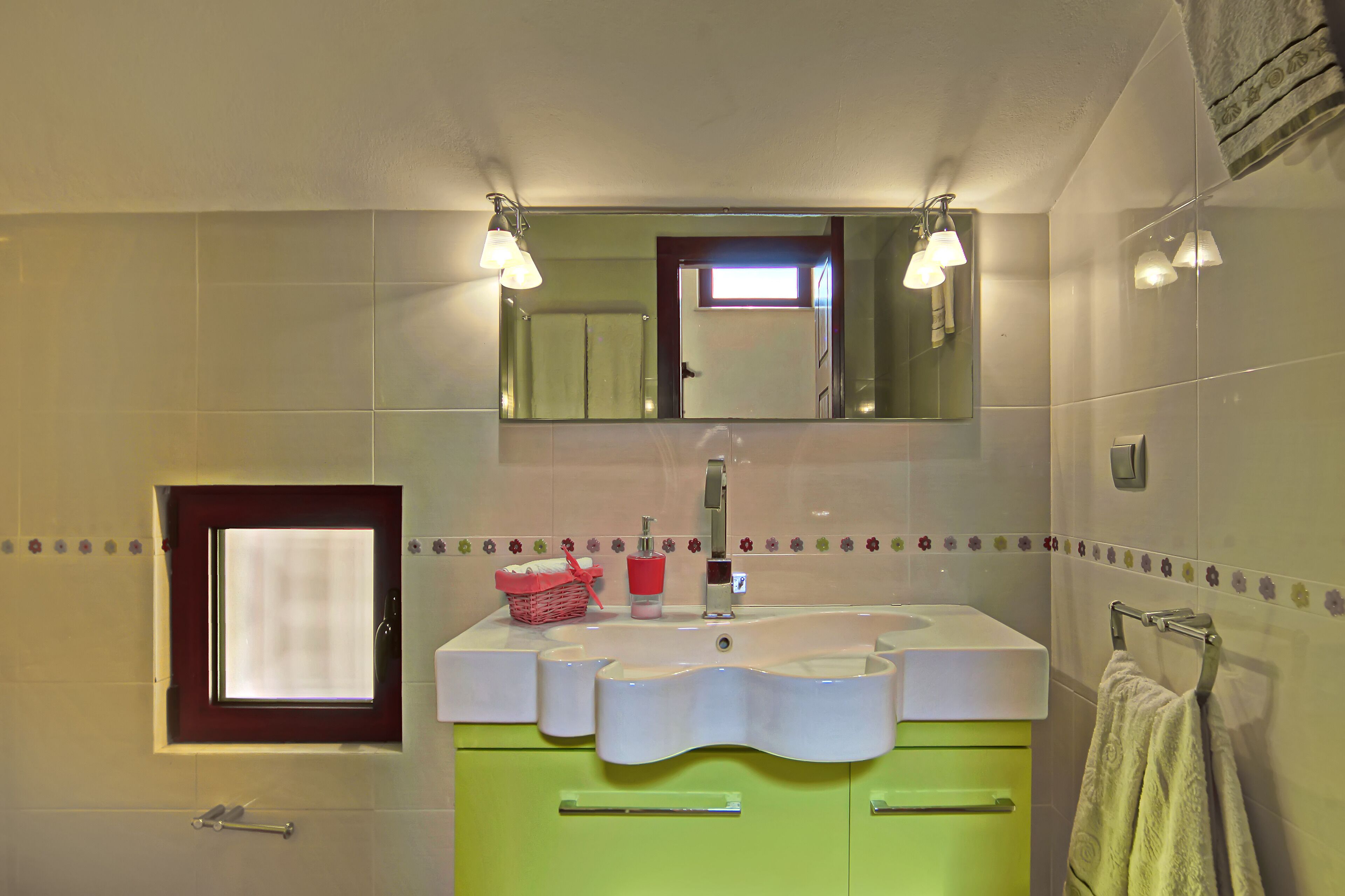 Une salle de bain avec un lavabo blanc, des meubles verts, un miroir et un porte-serviettes.