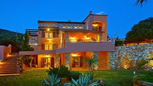 A multi-story house with a stone facade, multiple balconies, and a well-lit entrance.
