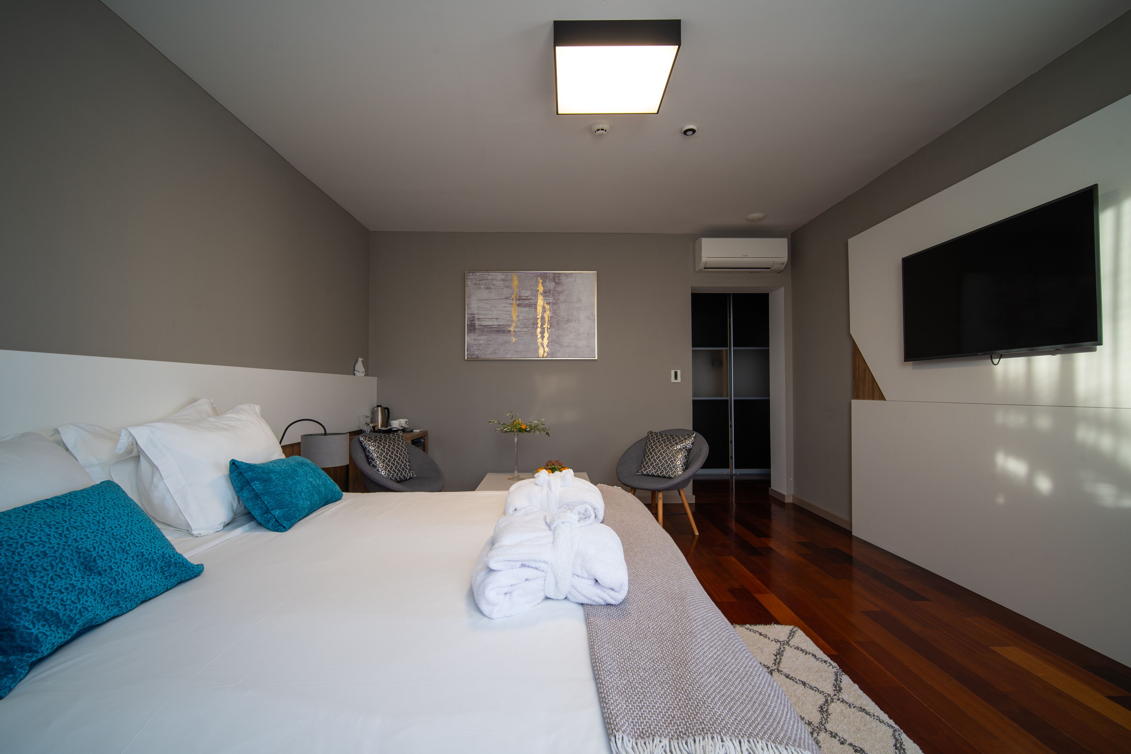 A modern hotel room with a large bed, a flat-screen TV, a seating area, and a view of the outdoors.