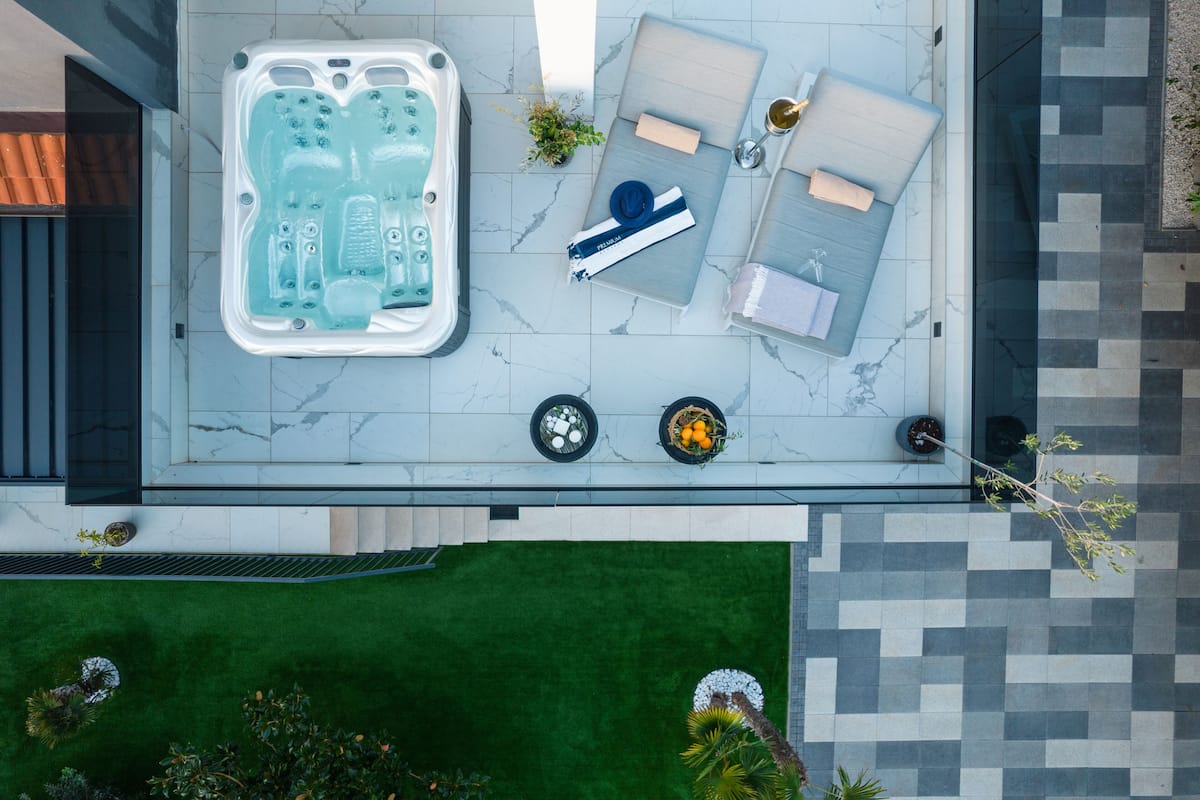 A rooftop terrace with a hot tub, lounge chairs, and a small table with a bottle and glasses.