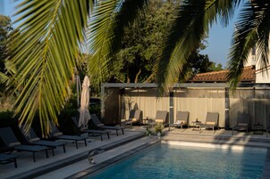 Uma área junto à piscina com espreguiçadeiras e um espaço de estar coberto.