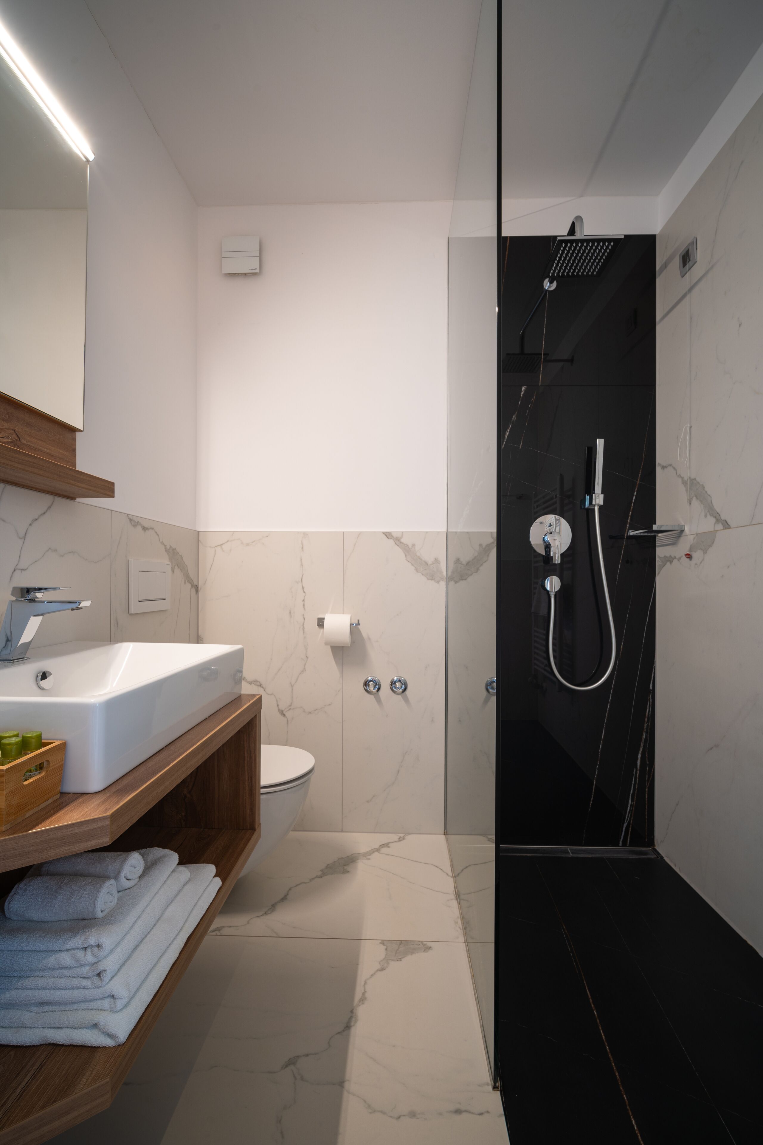 A modern bathroom with a glass-enclosed shower, a white sink, and a toilet.