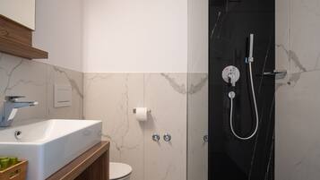 A modern bathroom with a glass-enclosed shower, a white sink, and a toilet.