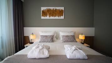 Une chambre d’hôtel avec un grand lit, deux lampes de chevet, des coussins à motifs et une œuvre d’art murale.