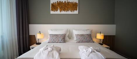 Ein Hotelzimmer mit einem großen Bett, zwei Nachttischlampen, gemusterten Kissen und einem Wandbild.