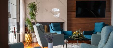 Una sala de estar moderna con un televisor grande, asientos cómodos, una planta en maceta y un jarrón decorativo.
