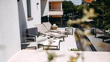 Un patio exterior moderno con sillones, una mesa y una planta en maceta.
