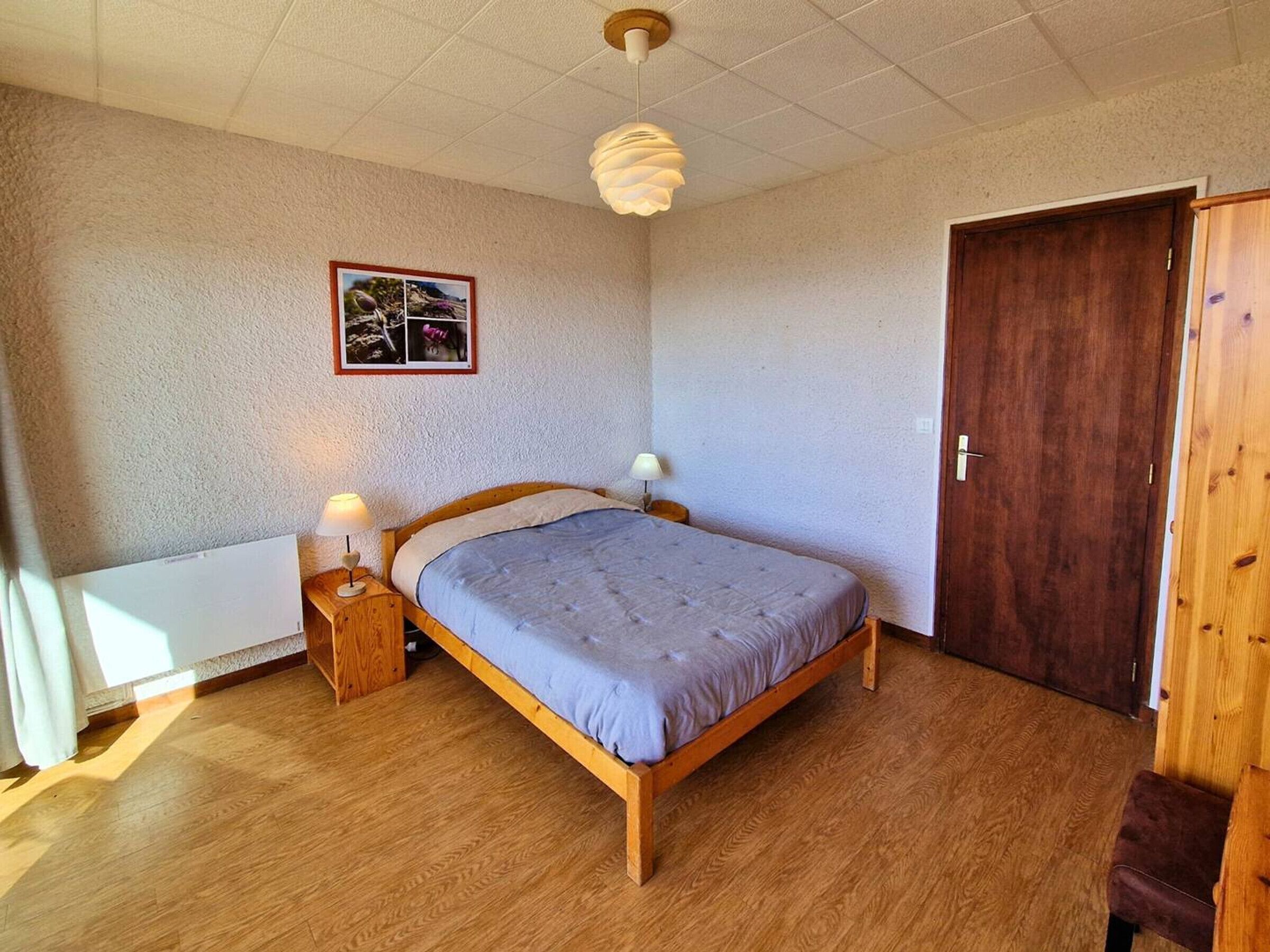 Ein Schlafzimmer mit einem hölzernen Bett, zwei Nachttischlampen, einem Holzschrank und einer Tür.