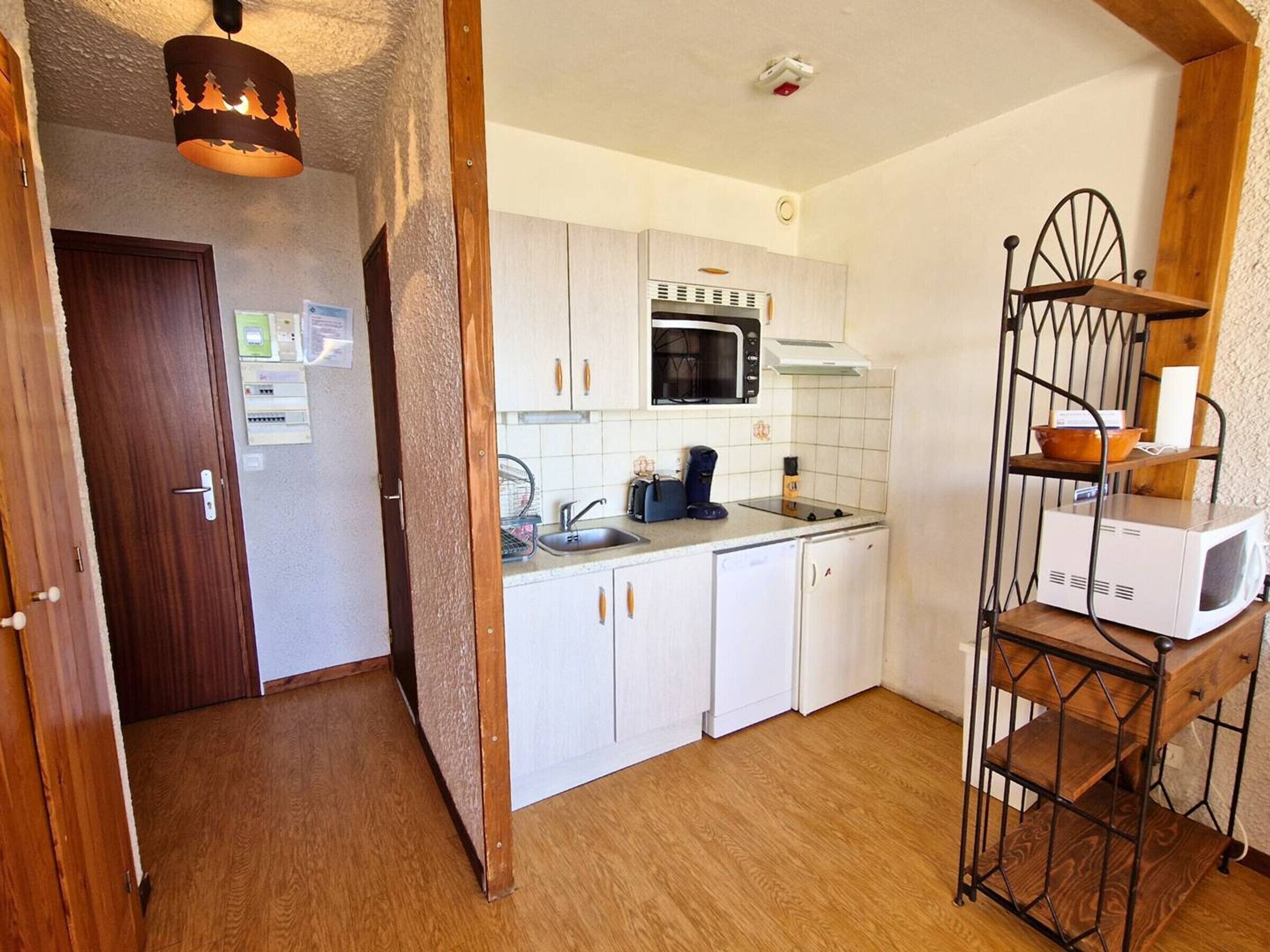 A compact kitchen with white cabinets, a microwave, and a coffee maker.