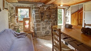 A rustic room with stone walls, wooden ceiling, a bed, a table, and a chair. - Feng Shui Cottage in Marlhes' Nature (Marlhes)