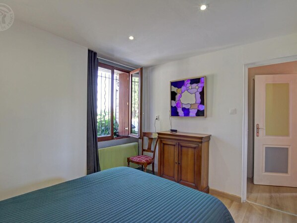 A bedroom with a bed, a chair, a cabinet, a window, and a painting on the wall.