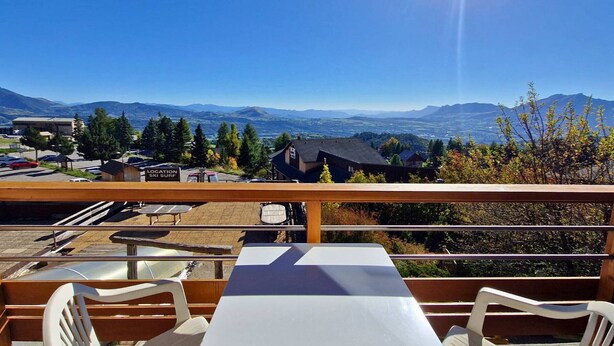A terrace with tables and chairs overlooking a scenic view of mountains and a parking area. - Apt 6 pers, south balcony, central, pets allowed, parking, WiFi, dishwasher (Saint-Michel-de-Chaillol)