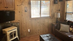 Ein gemütliches Wohnzimmer mit Holzwänden, einem Kamin, einem Fernseher und einer bequemen Couch.