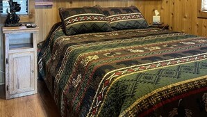 Ein Zimmer mit Holzwänden, einem Bett, einem Nachttisch und eingebauten Schränken.