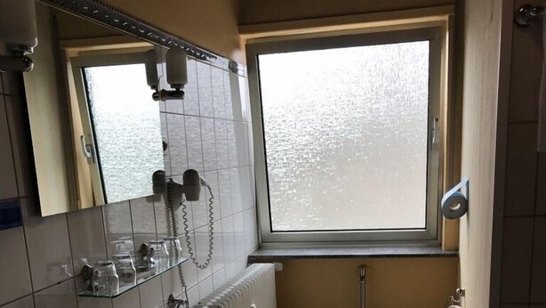 Ein kleines Badezimmer mit Waschbecken, Toilette und Fenster.