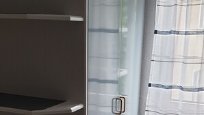 A room with a built-in wardrobe, a window with a striped curtain, and a pair of shoes on the floor. - City Hotel Kaiserhof (Saarbrücken)
