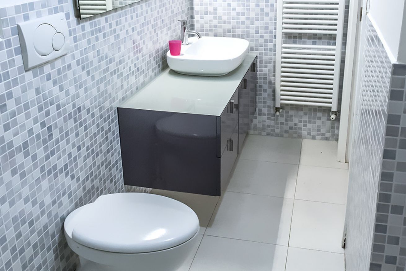Een badkamer met toilet, wastafel en spiegel.