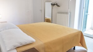 A bedroom with a bed, a radiator, and a window with blinds. - N198 - Numana, new three-room apartment with garden and swimming pool (Sirolo)