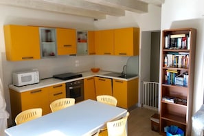 A compact kitchen with yellow cabinets, a microwave, a sink, and a dining area with a table and chairs.