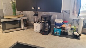 A kitchen with a microwave, toaster, coffee maker, and various kitchen items on the counter.