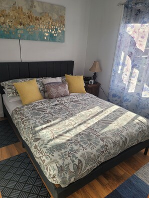 A bed with a floral bedspread, a headboard, and multiple pillows. - Cozy quiet place next to hwy smart tv+wifi+netflix (Edmundston)