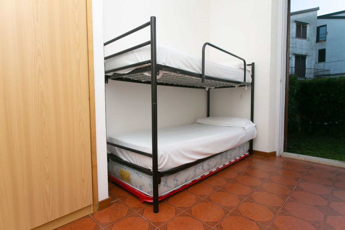 A bunk bed in a room with tiled flooring and a view of a building outside.