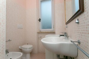 Un bagno con toilette, bidet e lavandino.