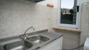 A kitchen with a double stainless steel sink, a window above the sink, and a tiled backsplash. - M087 - Marcelli, three-room apartment with terrace at the Mareverde residence (Marcelli)
