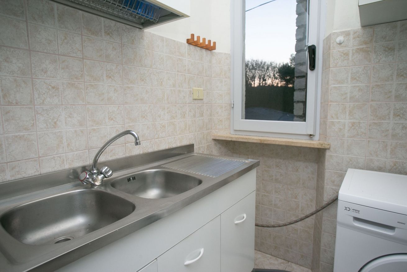 A kitchen with two sinks, a window, and a washing machine.