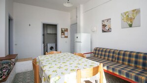A room with a dining table, a sofa, a washing machine, and a refrigerator. - M087 - Marcelli, three-room apartment with terrace at the Mareverde residence (Marcelli)
