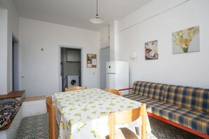 A room with a dining table, a sofa, a washing machine, and a refrigerator.