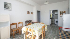 A dining area with a table and chairs, a kitchen in the background, and a patterned floor. - M087 - Marcelli, three-room apartment with terrace at the Mareverde residence (Marcelli)
