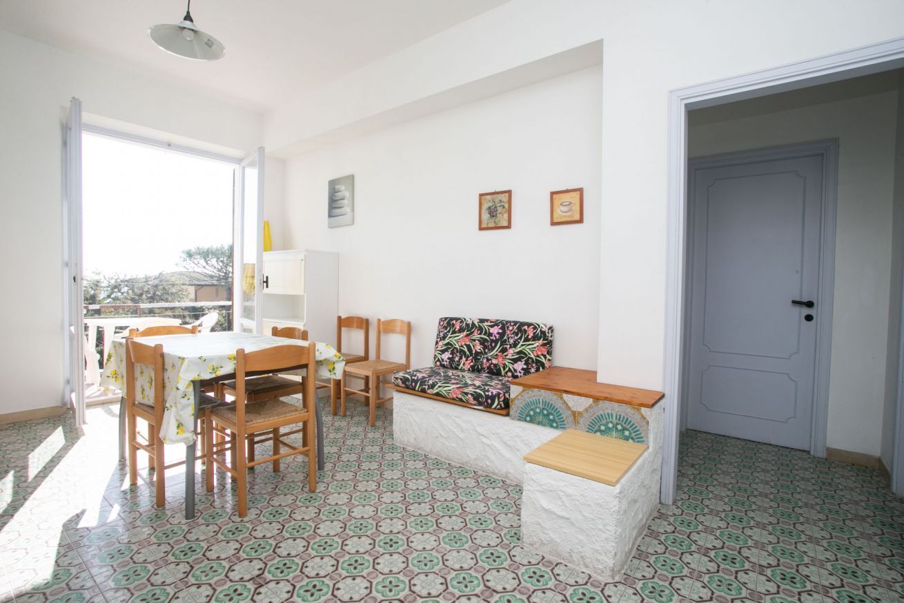 Una habitación con una mesa de comedor, sillas, un sofá, un banco, una puerta y una pared con cuadros.