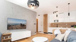 A modern living room with a sofa, a small round table, and a TV mounted on the wall.
