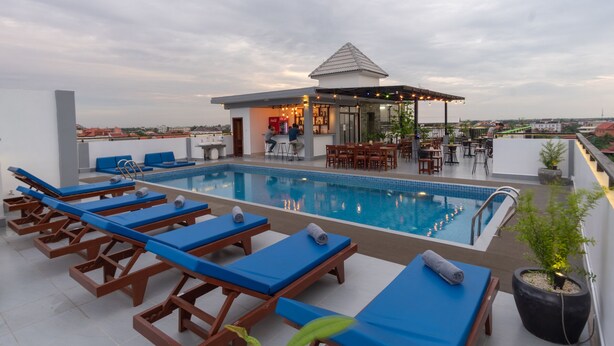 Ein Poolbereich auf dem Dach mit Liegestühlen, einer Bar und einem kleinen Pavillon.