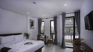 Ein Hotelzimmer mit Bett, Schreibtisch, Stuhl, Fernseher und einem Balkon mit Blick sowie einer Obstschale.