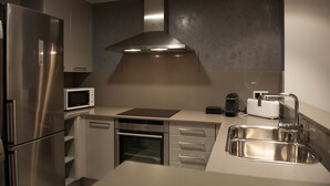 Une cuisine moderne équipée d’appareils électroménagers en acier inoxydable, d’un four encastré, d’un four à micro-ondes et d’un évier.