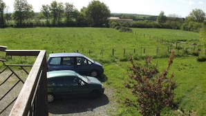 Ein grünes Feld mit zwei geparkten Autos in der Nähe eines Holzzauns.