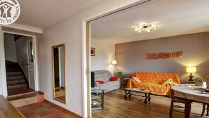 Ein Wohnzimmer mit einer Couch, einem Couchtisch und einem Esstisch. Eine Treppe führt in einen anderen Raum.