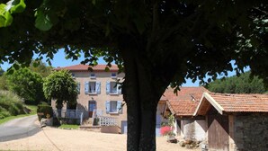 Ein Gebäude mit rotem Ziegeldach, einer Steinmauer und einem Baum im Vordergrund.