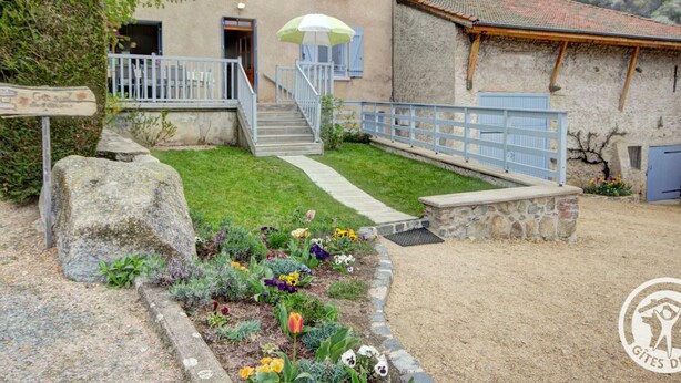 Ein zweistöckiges Haus mit Vorgarten, einer zur Eingangstür führenden Treppe und einem kleinen Gebäude mit Ziegeldach.