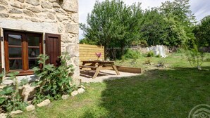 Un bâtiment en pierre avec une fenêtre en bois et une table de pique-nique dans la cour.