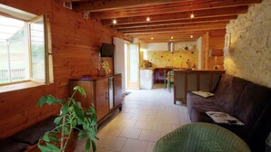Un intérieur en bois comprenant une cuisine, un coin repas et un salon avec un canapé et un fauteuil vert.
