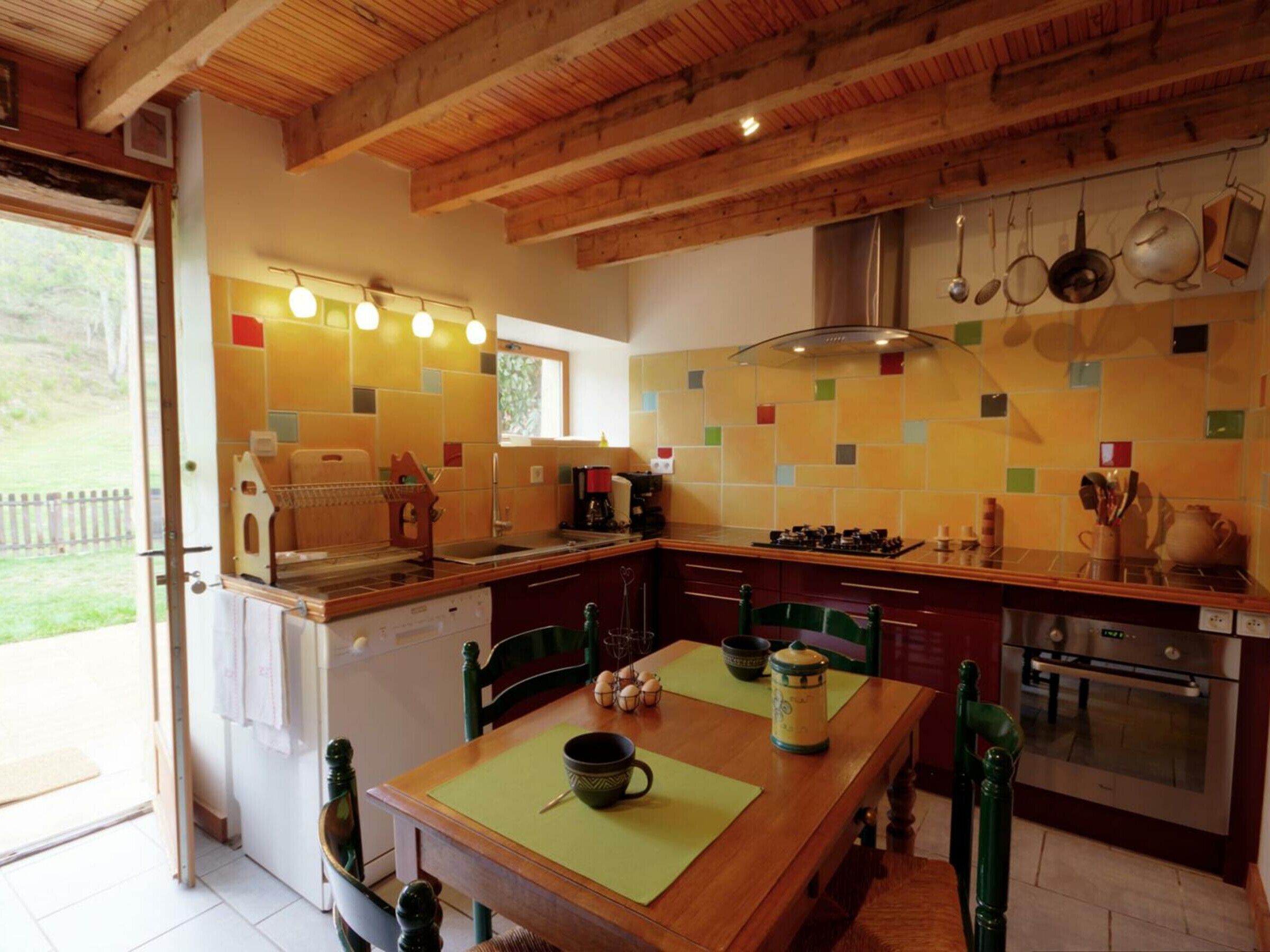 Une cuisine avec des poutres en bois, un poêle et des casseroles suspendues.