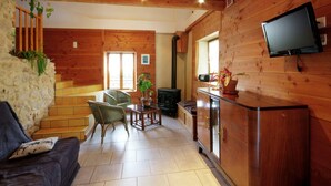 Un intérieur en bois avec un canapé, des fauteuils, un téléviseur et une cheminée.