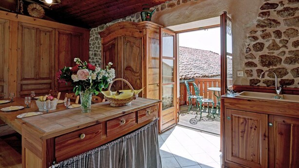 Una cucina rustica con mobili in legno, una grande isola con un vaso di fiori e vista sull'esterno.