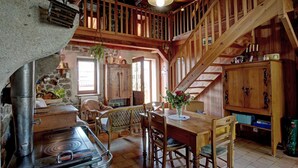 Un'accogliente interni in legno rustico con camino in pietra, tavolo da pranzo in legno e una scala.