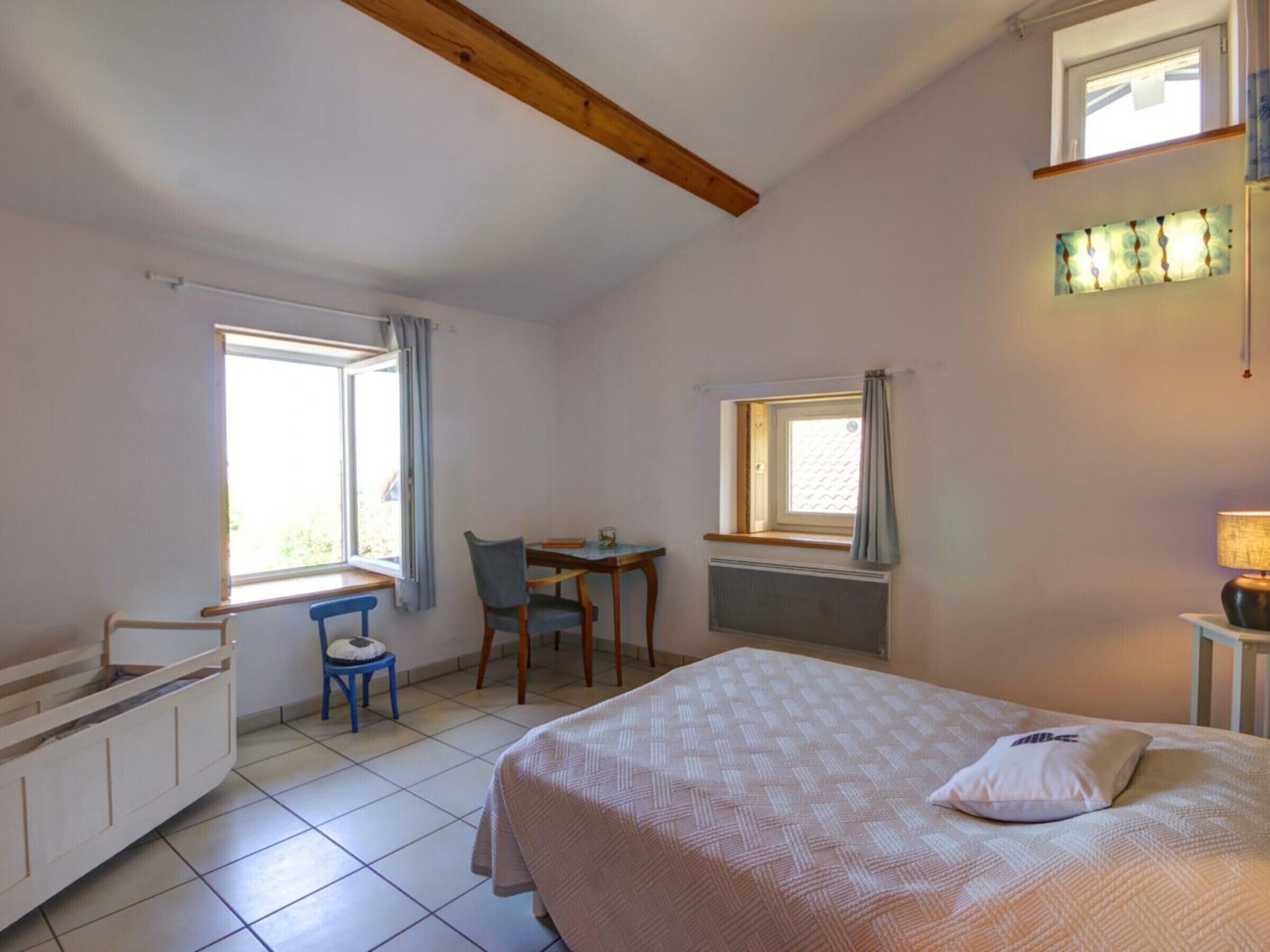 A bedroom with a bed, a desk, a chair, and a window.